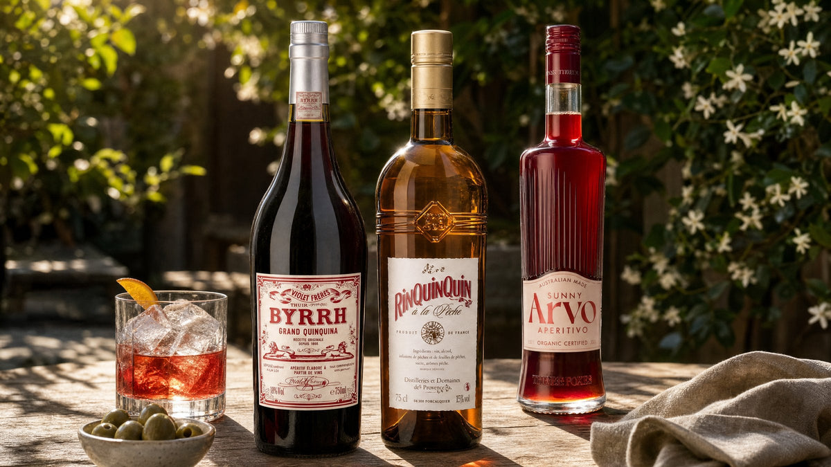 Byrrh, RinQuinQuin à la Pêche and Three Foxes Sunny Arvo Aperitivo on a garden table with an aperitif on ice and olives