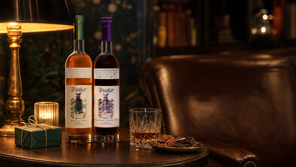 Willett Family Estate Rye and Willett 12 Year bourbon on a walnut sideboard by candlelight with pecans and a wrapped gift