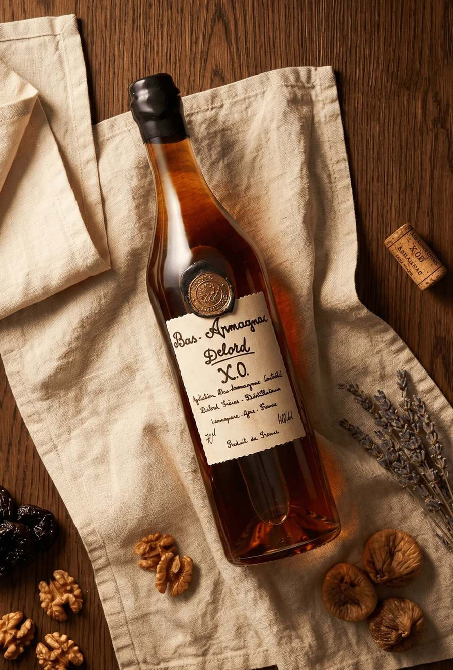 Bottle of Delord Bas-Armagnac XO on linen with walnuts, figs and lavender